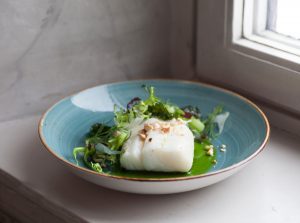 Uppläggning mat torsk och broccoli, blått fat ståendes i fönster