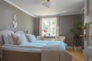 hotellrum med dubbelsäng med ett beige överkast och khakifärg på väggarna.