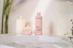 Spaprodukter Skeyndor i rosa flaska, en rosa två, 2 vita ljus på ett vitt handfat